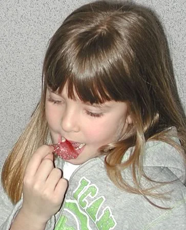 A girl inserting her retainer: For elementary school children, ‘show and tell’ is an effective way to gain compliance.